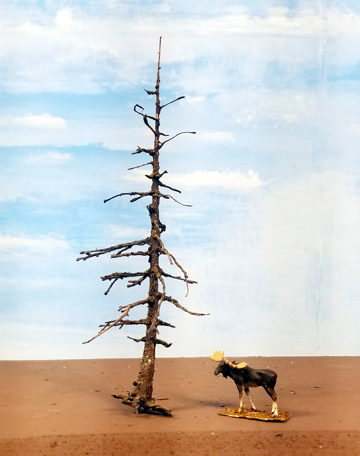An older version of a Coastman's 5 inch model dead snag ghost tree with a root system and HO scale moose on a plain diorama board.