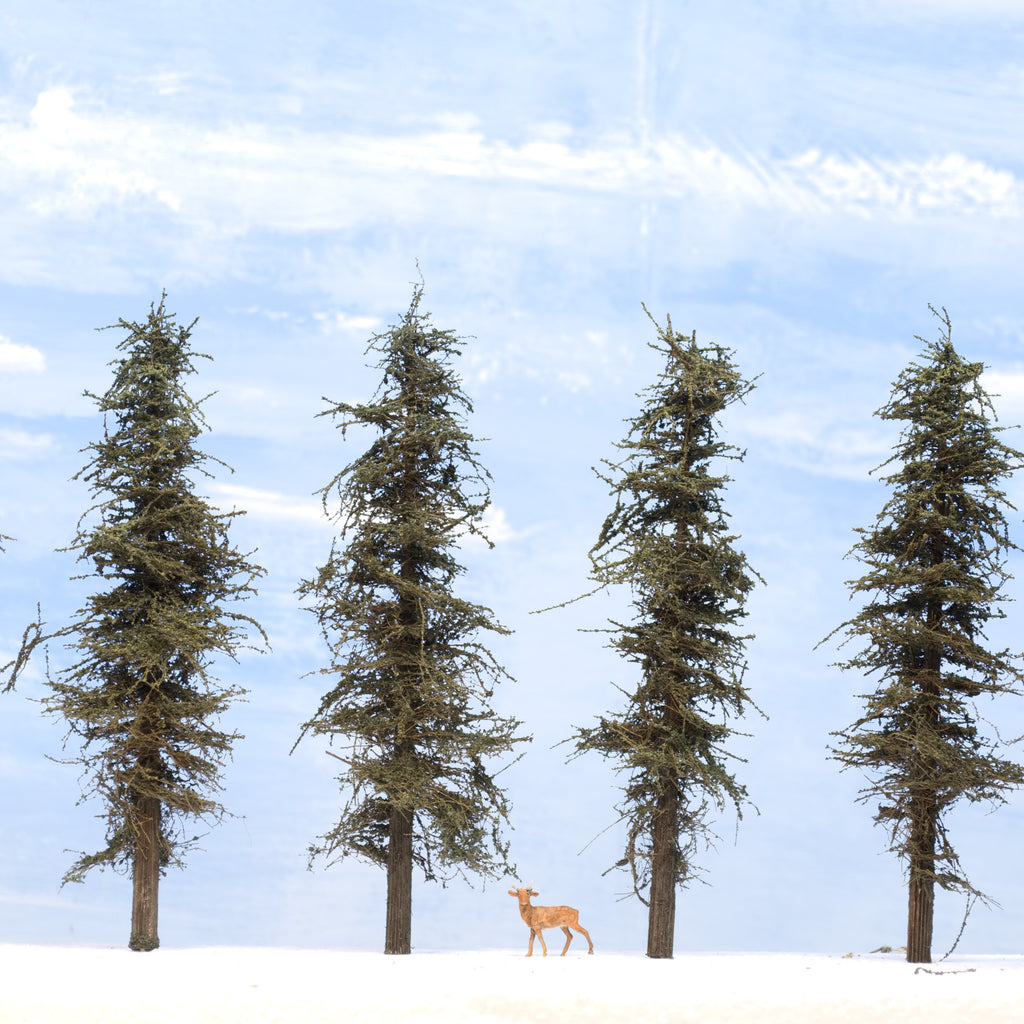 Examples of 7 inch tall Standard Fir Trees on a white foam base with HO scale deer taken at eye level. 