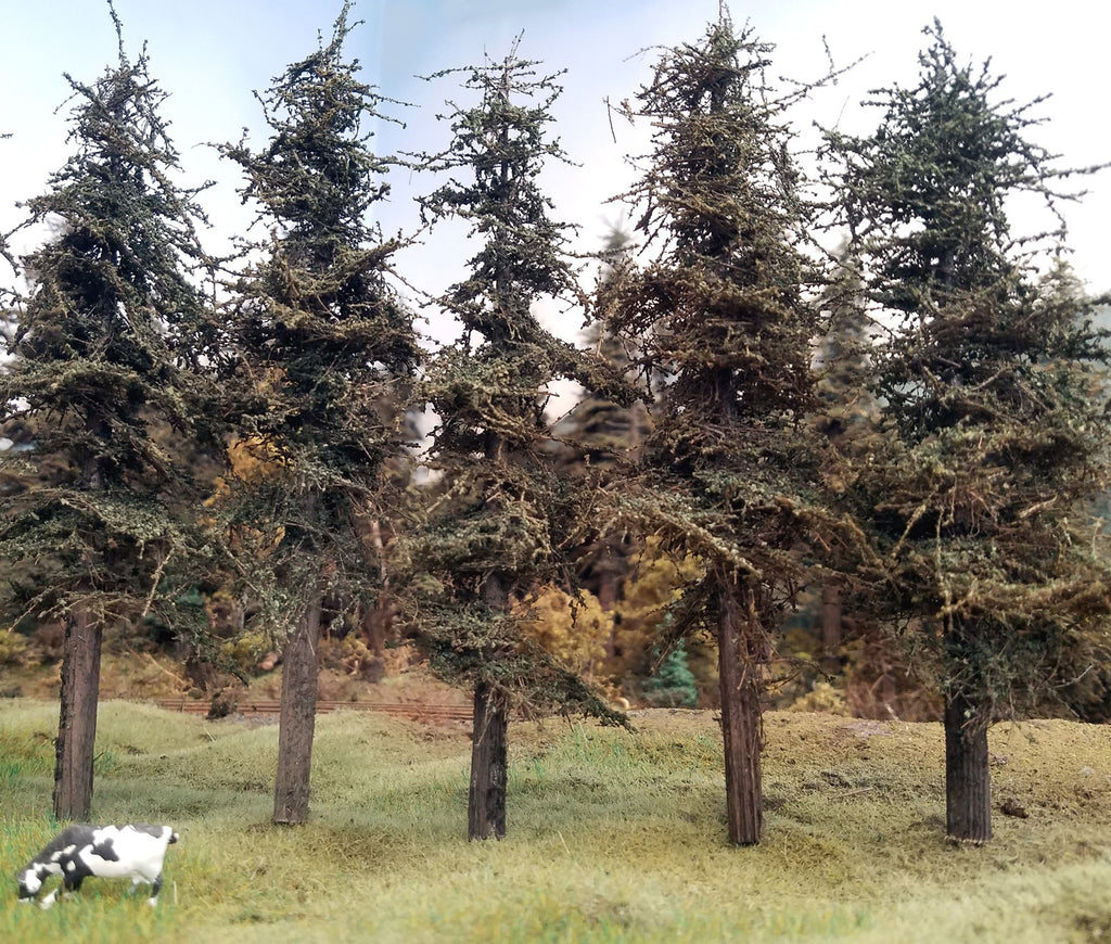 7 inch tall Standard Fir Trees quantity five on HO Scale Railroad Layout with a Holstein Dairy Cow in the foreground. 