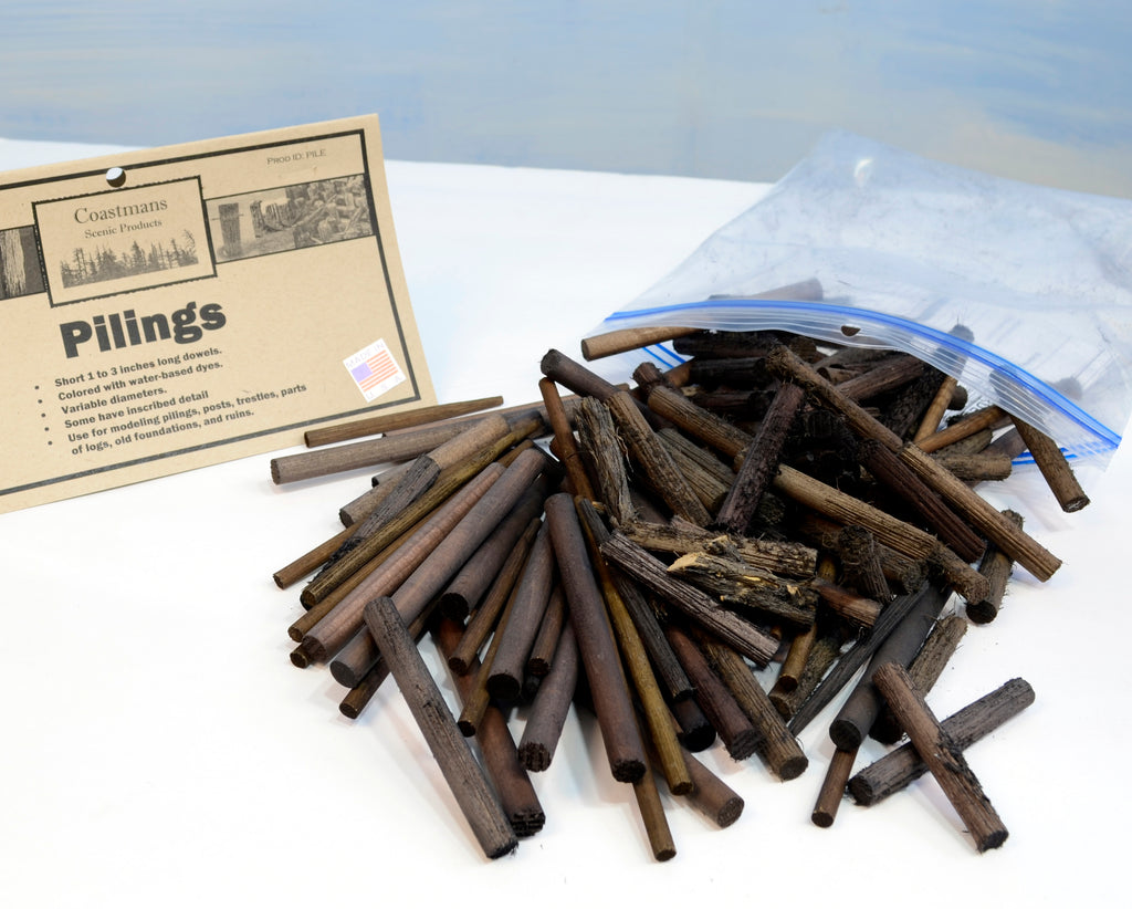 Pile of Coastman's wooden pilings with spread out on a white surface suitable for HO, O, and S scale model railroading and dioramas