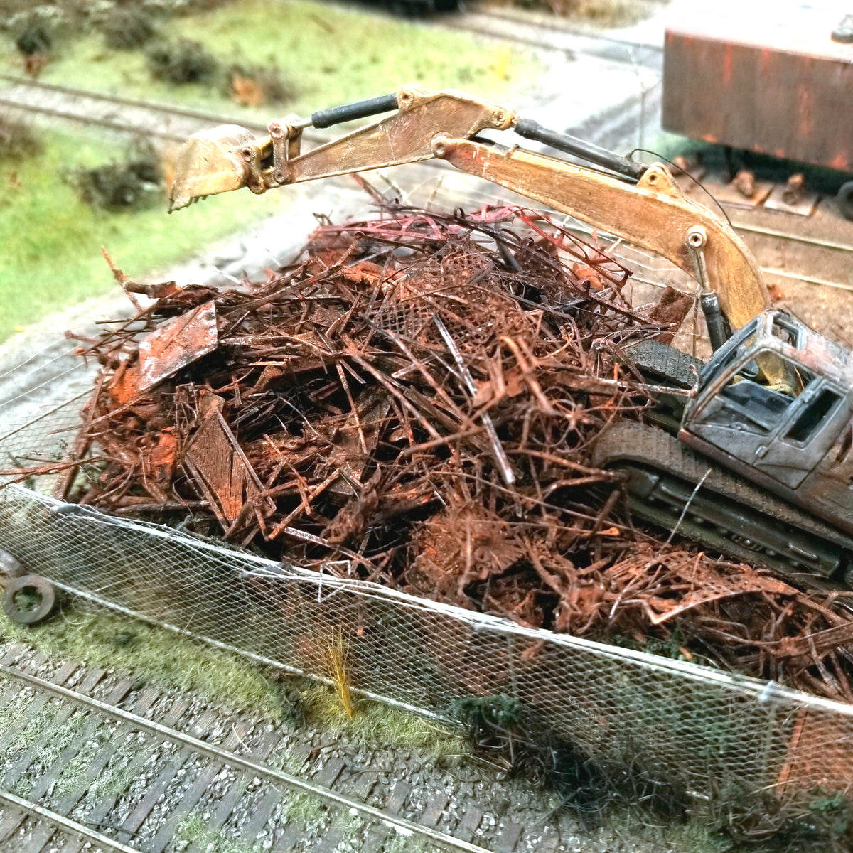 Citrus Recyclers at work on Roger's HO scale OCRX layout with a backhoe hovering over the shredded scrap metal which is actually made of PLA, with HO scale railroad track for scale reference. Photo by Roger Rasmussen, CSP LLC, 97465.