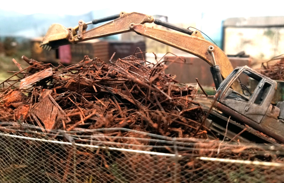 Citrus Recyclers at work on Roger's HO scale OCRX layout with a backhoe hovering over the shredded scrap metal which is actually made of PLA, with HO scale railroad cars in the background. Photo by Roger Rasmussen, CSP LLC, 97465.