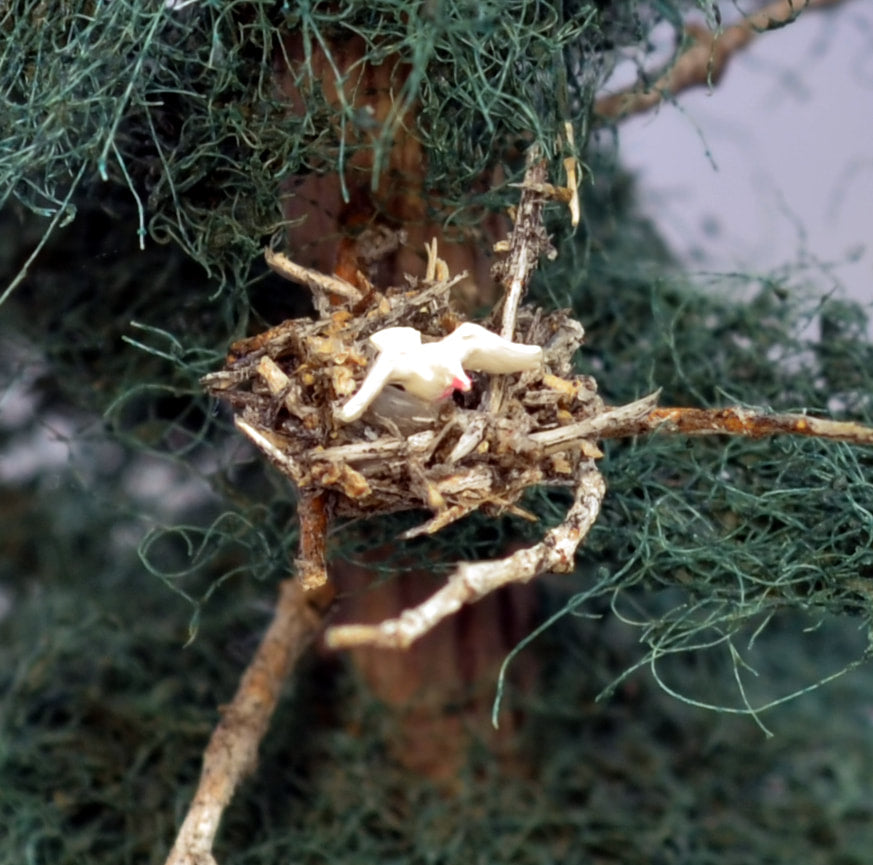 Bird in a tiny HO scale bird's nest made by Coastman's Scenic Products in older style fir tree made with scrubber foliage