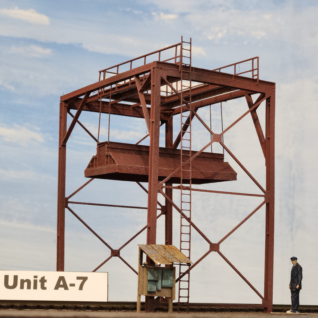 Model of a wood chip loader in HO scale with 'Unit A-7' label against a light blue background