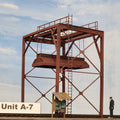 Model of a wood chip loader in HO scale with 'Unit A-7' label against a light blue background