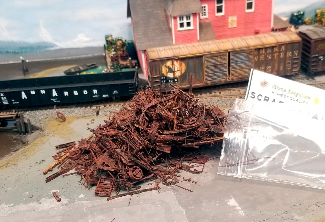 Coastman's HO scale SCRAP METAL, photo taken on Roger's OCRX HO scale model railroad layout, showing contents including metal rims, grating, matresses, and shredded metal which is actually made of PLA, with HO scale railroad cars in the background.