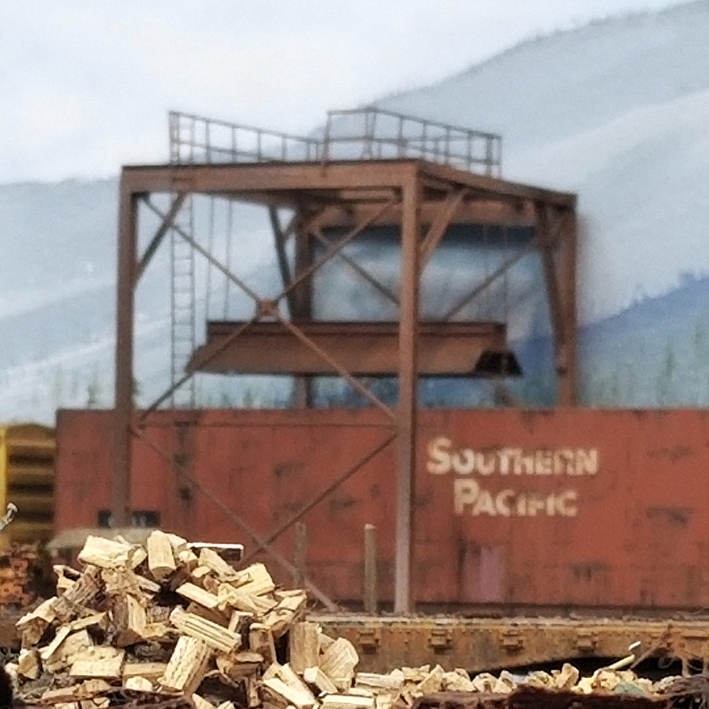 Poorly focused photograph of HO scale wood chip loader filling wood chips into an HO scale wood chip hopper gondola on Roger's HO scale Oregon Coast layout.